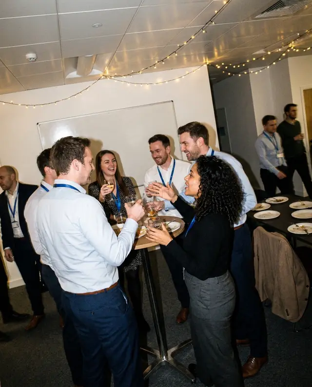 Coworkers laughing over drinks at an end-of-year work party